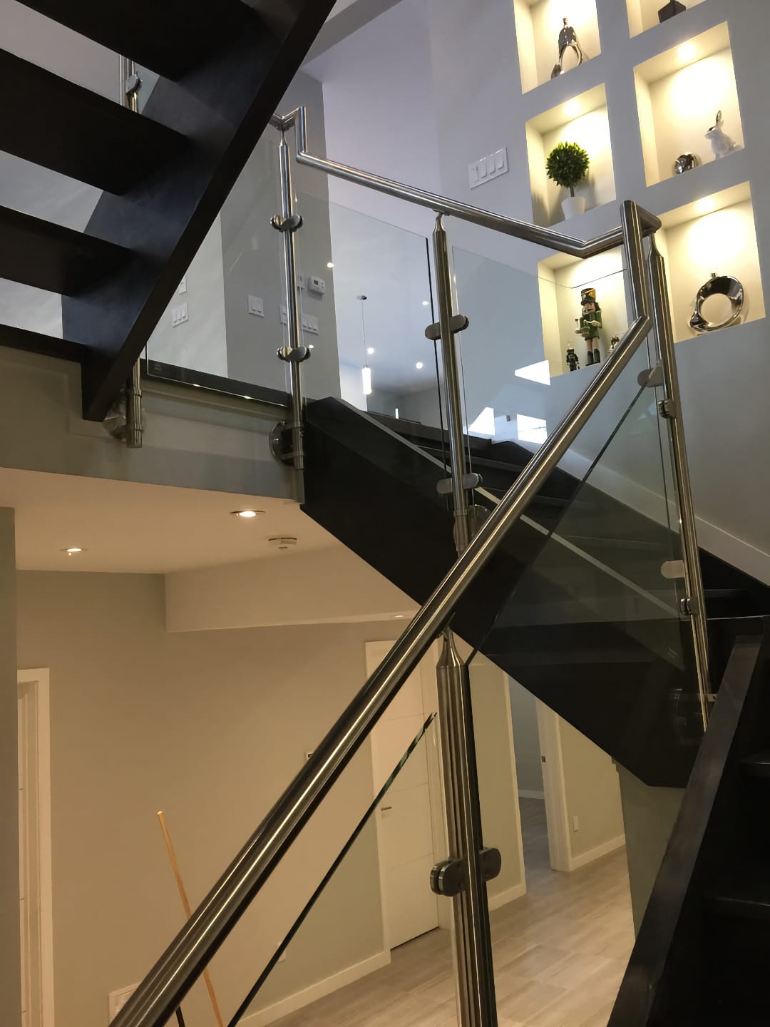 Black wooden stairs with stainless steel railing and glass
